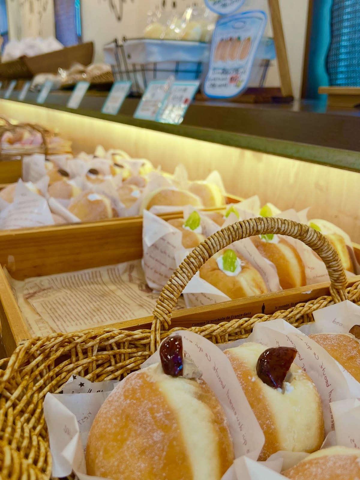 ポルボロンのカゴに並ぶクリーム系のパンと店内の棚