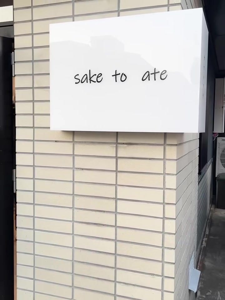 サケトアテの白タイル壁と sake to ate の看板