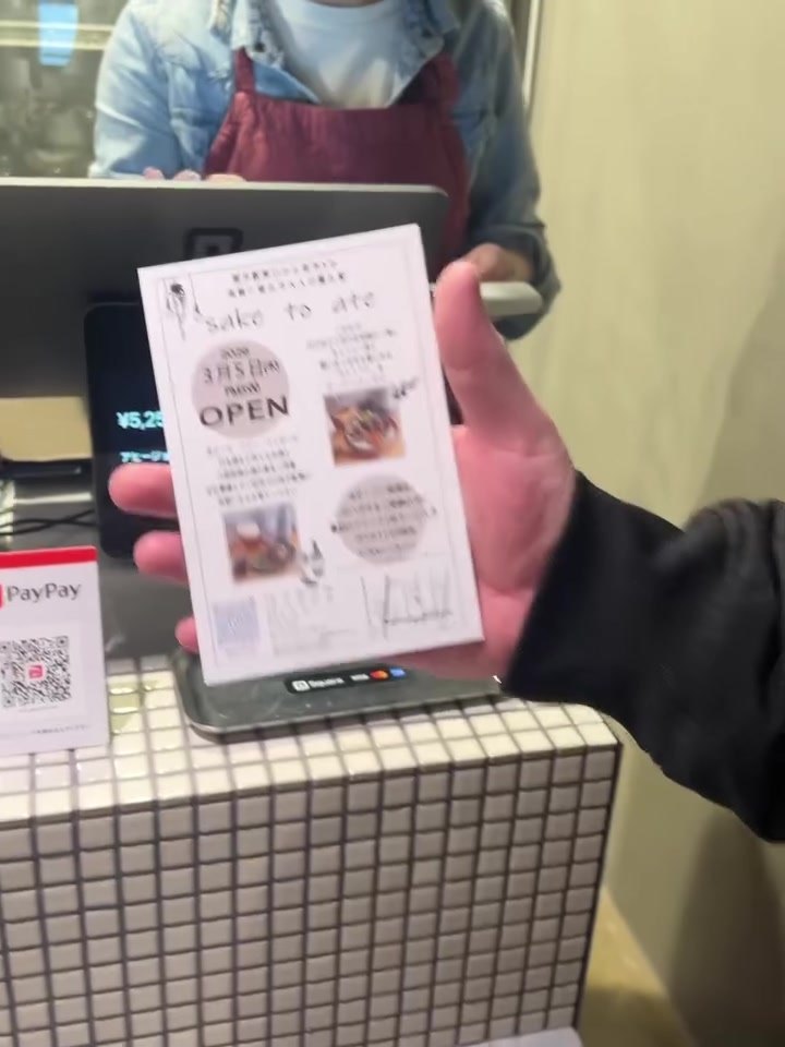 サケトアテのレジでオープン案内のハガキを受け取る